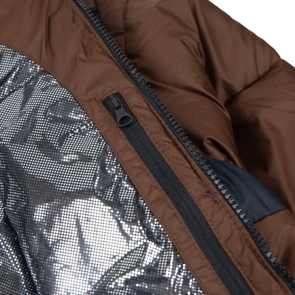 Close-up of a brown Columbia jacket with a black zipper and silver lining.